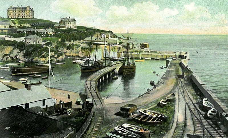 Old coloured illustration of Newquay harbour with sailing ships, the central jetty and the mineral railway tracks