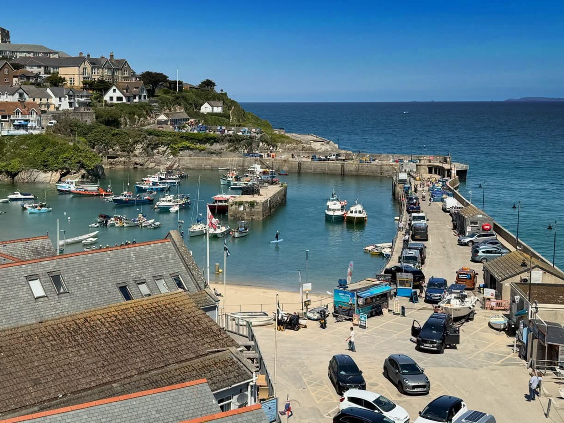 Boats in Newquay harbour at high tide with fishing boats and leisure craft and the coast beyond