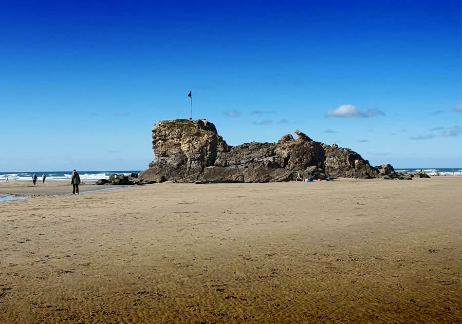 Chapel Rock and its flagpole on Perranporth beach at low tide